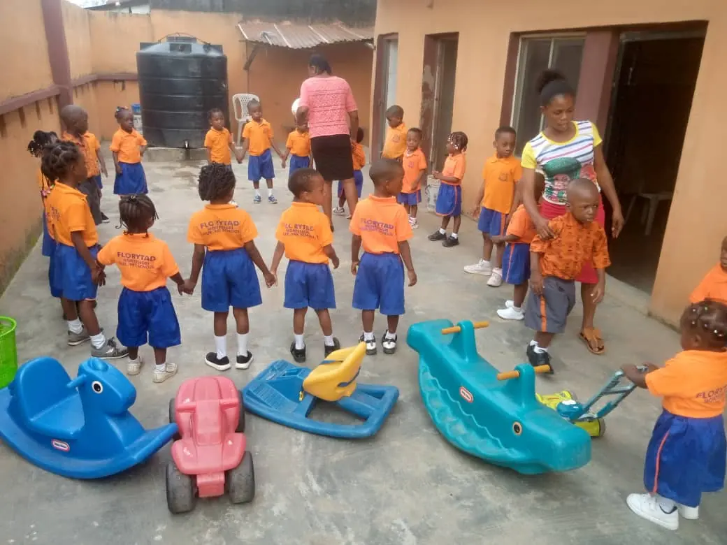 Nursery children in a circle in the school courtyard with rocking toys